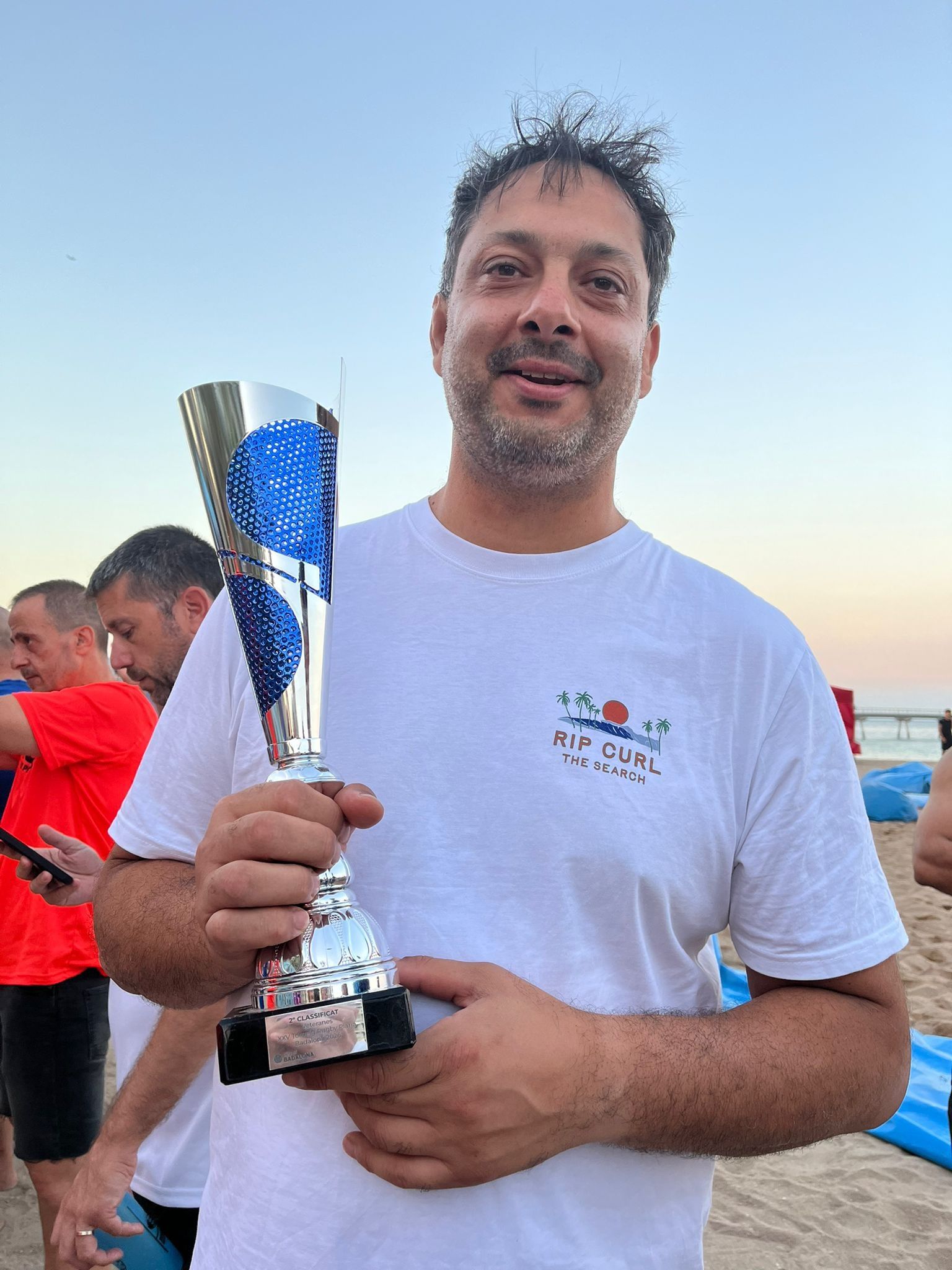 Un jugador somrient a la platja al capvespre